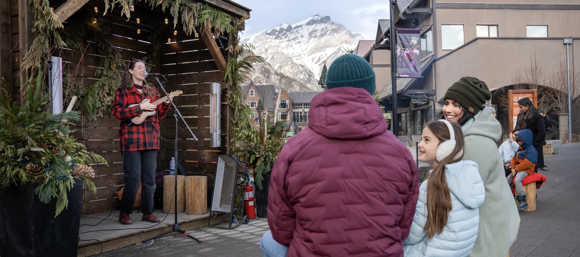 A family watching a local musician on Bear Street in Banff during the SnowDays Festival