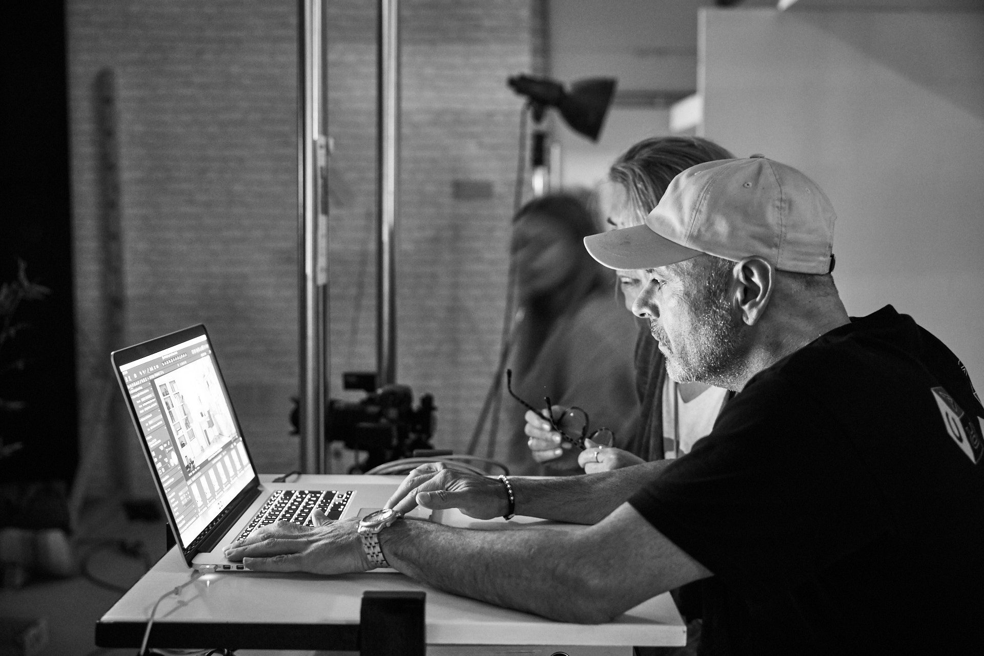 Fotograf am Rechner und betrachtet Bilderoutput mit Kollegen