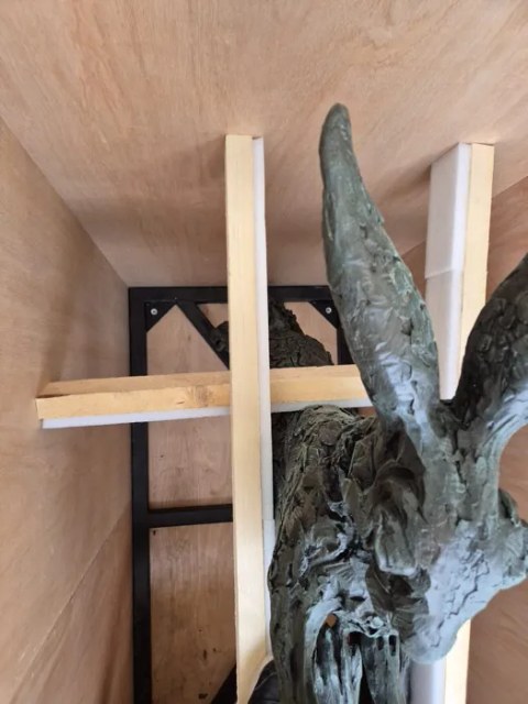 Large bronze sculpture braced on timber beams inside its crate