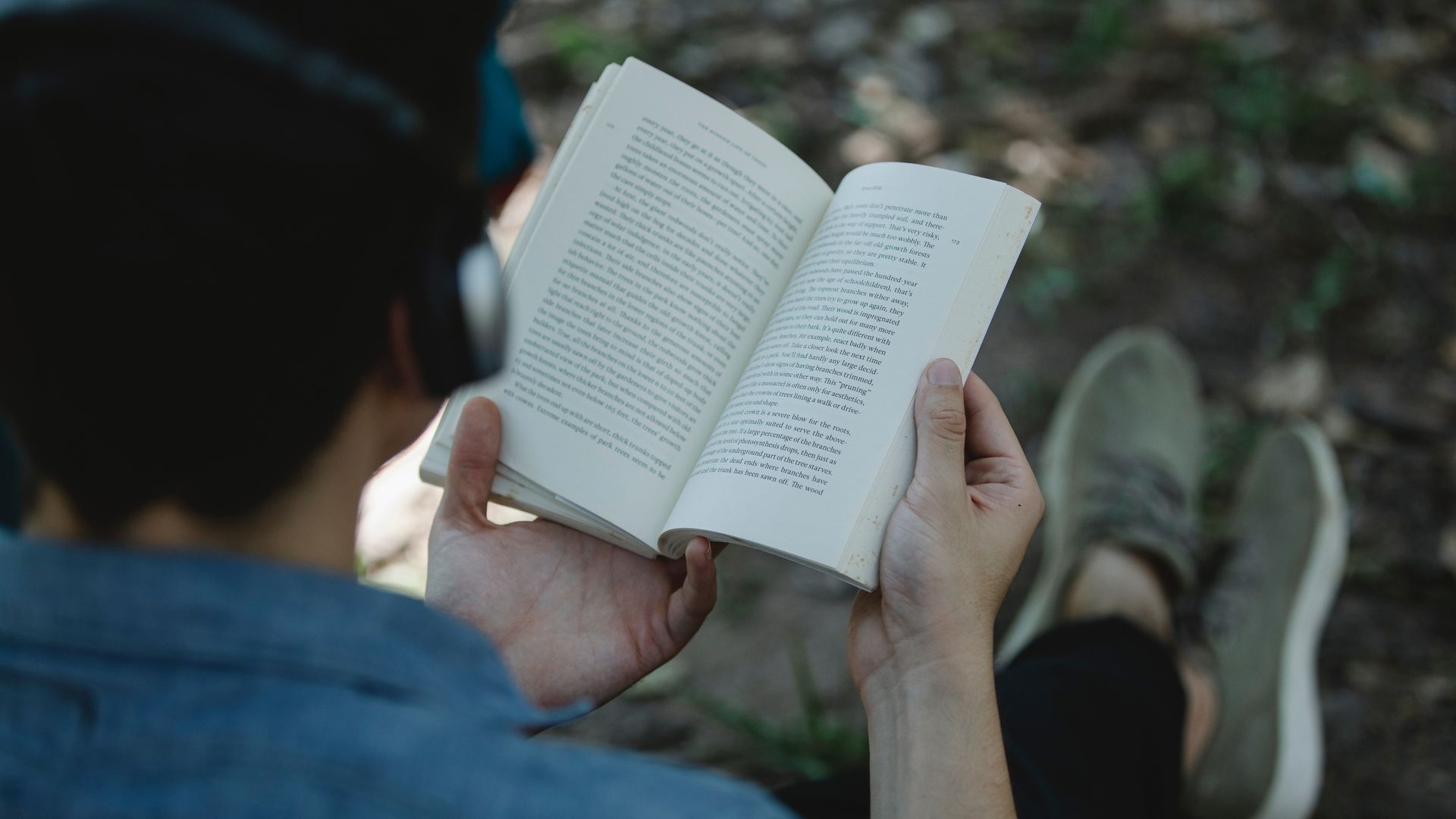 Mann som leser en bok mens han har på hodetelefoner