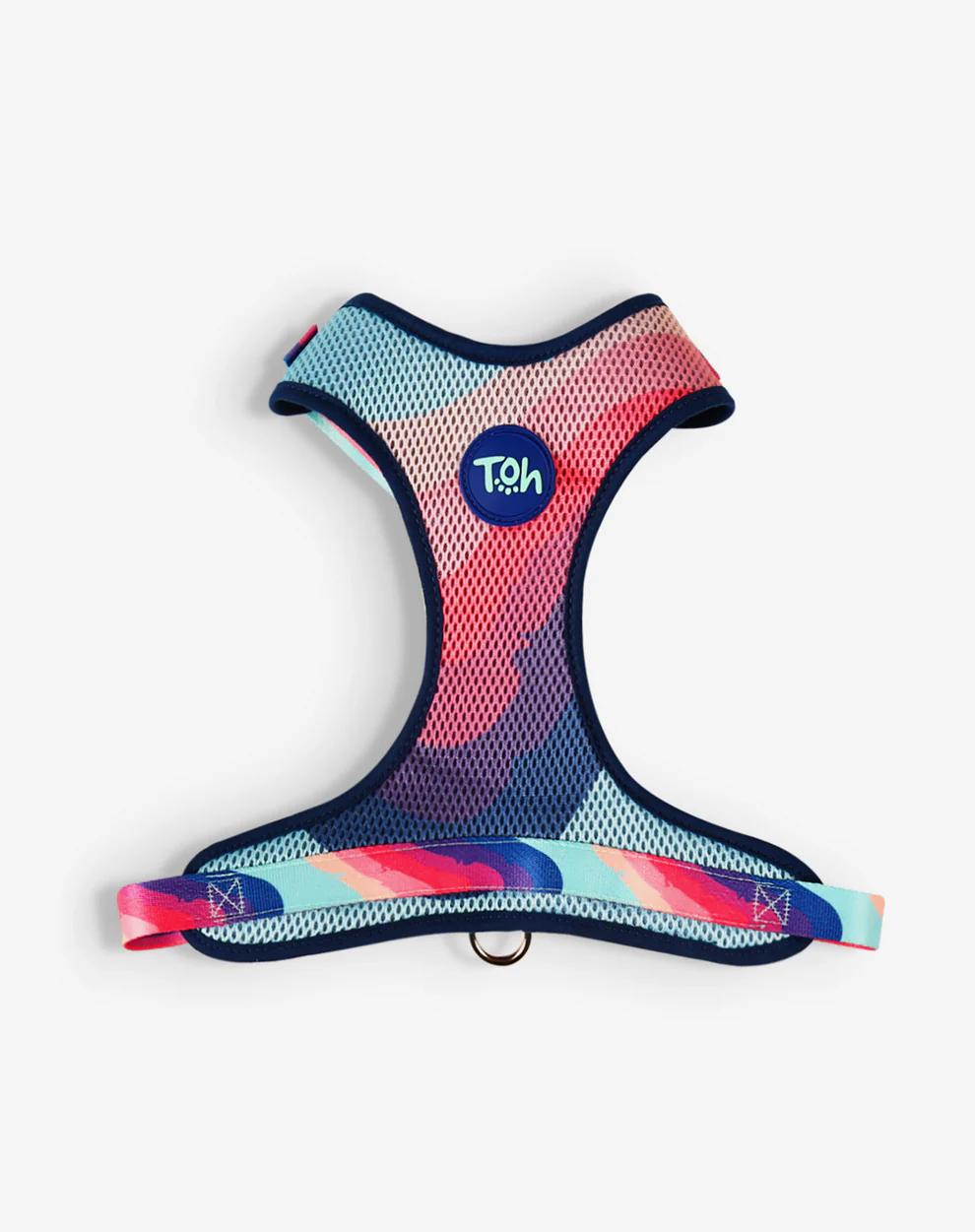 A colorful, multi-patterned dog harness made from breathable mesh fabric with an adjustable strap and a D-ring for leash attachment, featuring a 'T.Oh' brand logo.