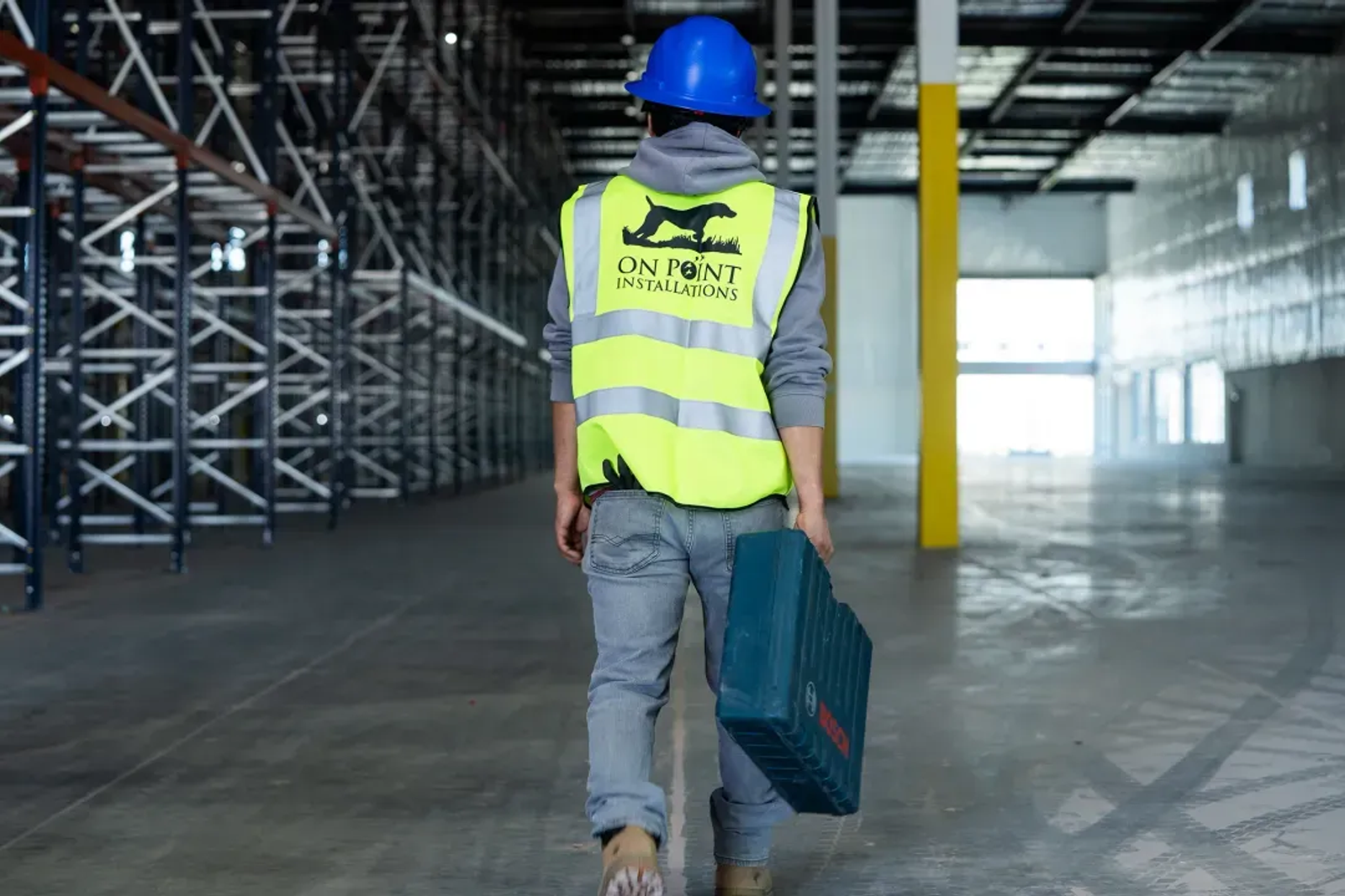 On Point Installations crew member walking a warehouse floor with tools
