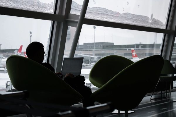 Traveler in airport lounge, working on laptop.