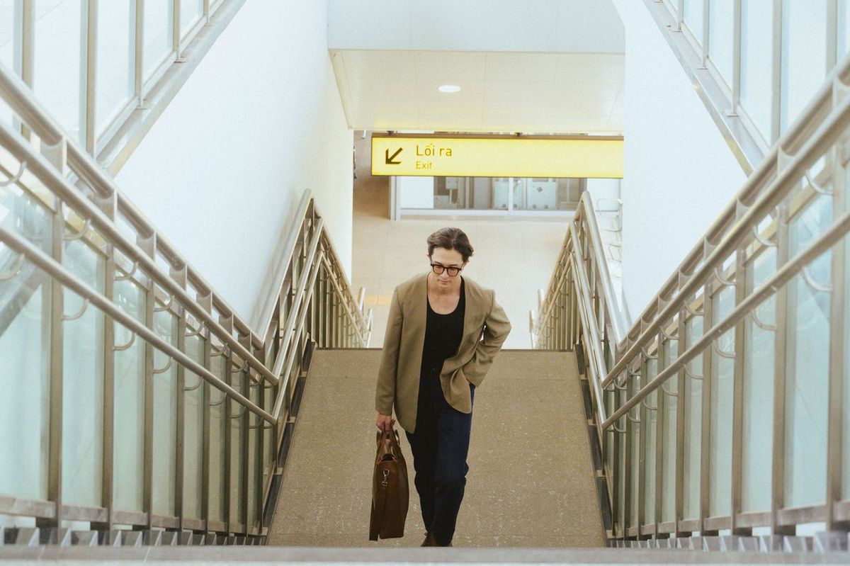 Woman with briefcase walking up airport stairs.
