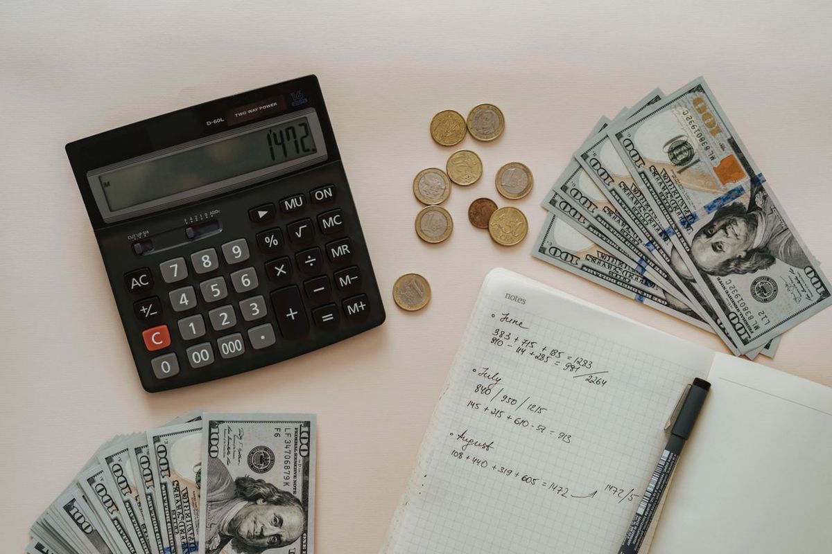 Calculator, cash, coins, and notebook with budget notes.