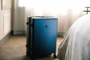 Suitcase on hotel room floor next to bed