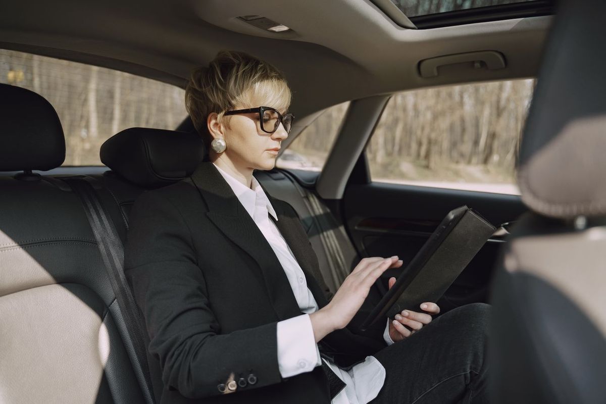 Professional in car with tablet, focused on screen while traveling.