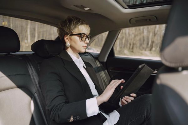 Professional in car with tablet, focused on screen while traveling.