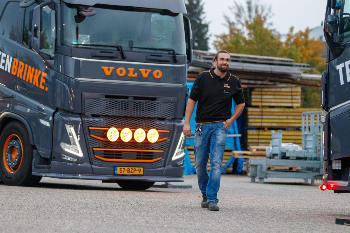 Truck driver walking near a Volvo truck in an industrial area.