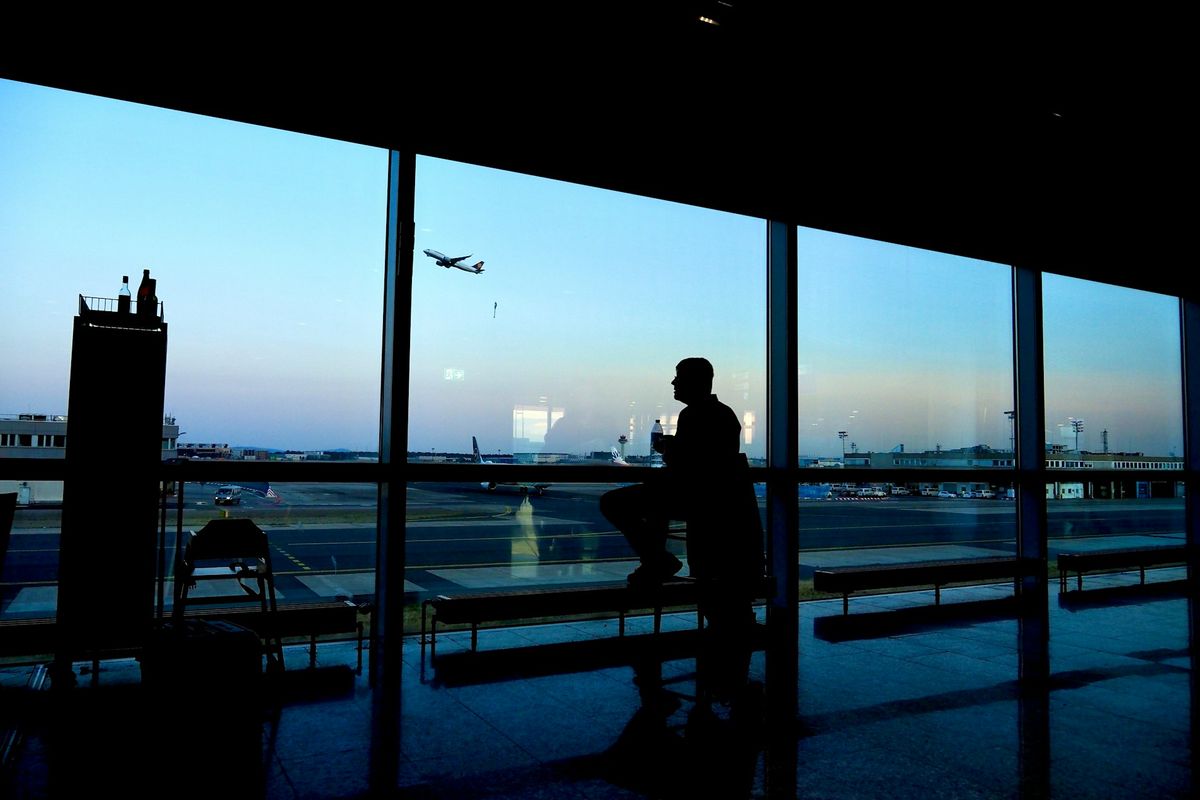 Traveler silhouetted in airport window with plane.