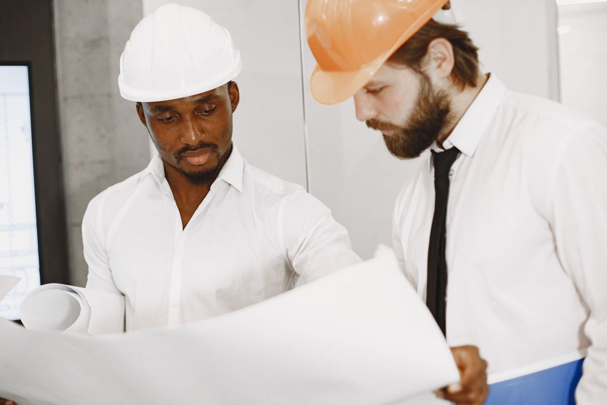 Two engineers in helmets reviewing construction blueprints.