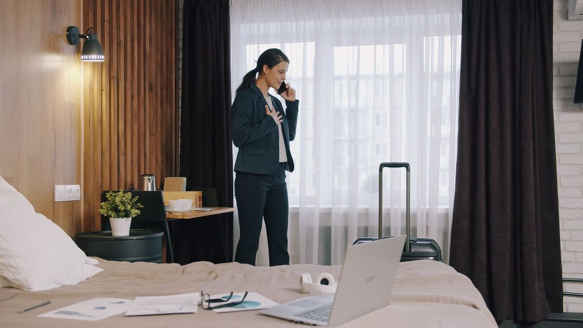 Business traveler in hotel room on phone.