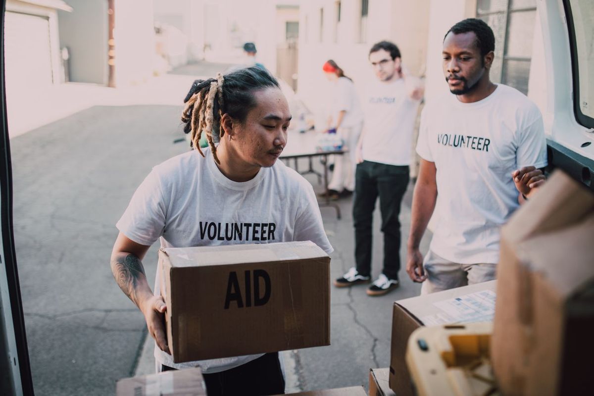 Volunteers unloading aid boxes from vehicle outdoors.