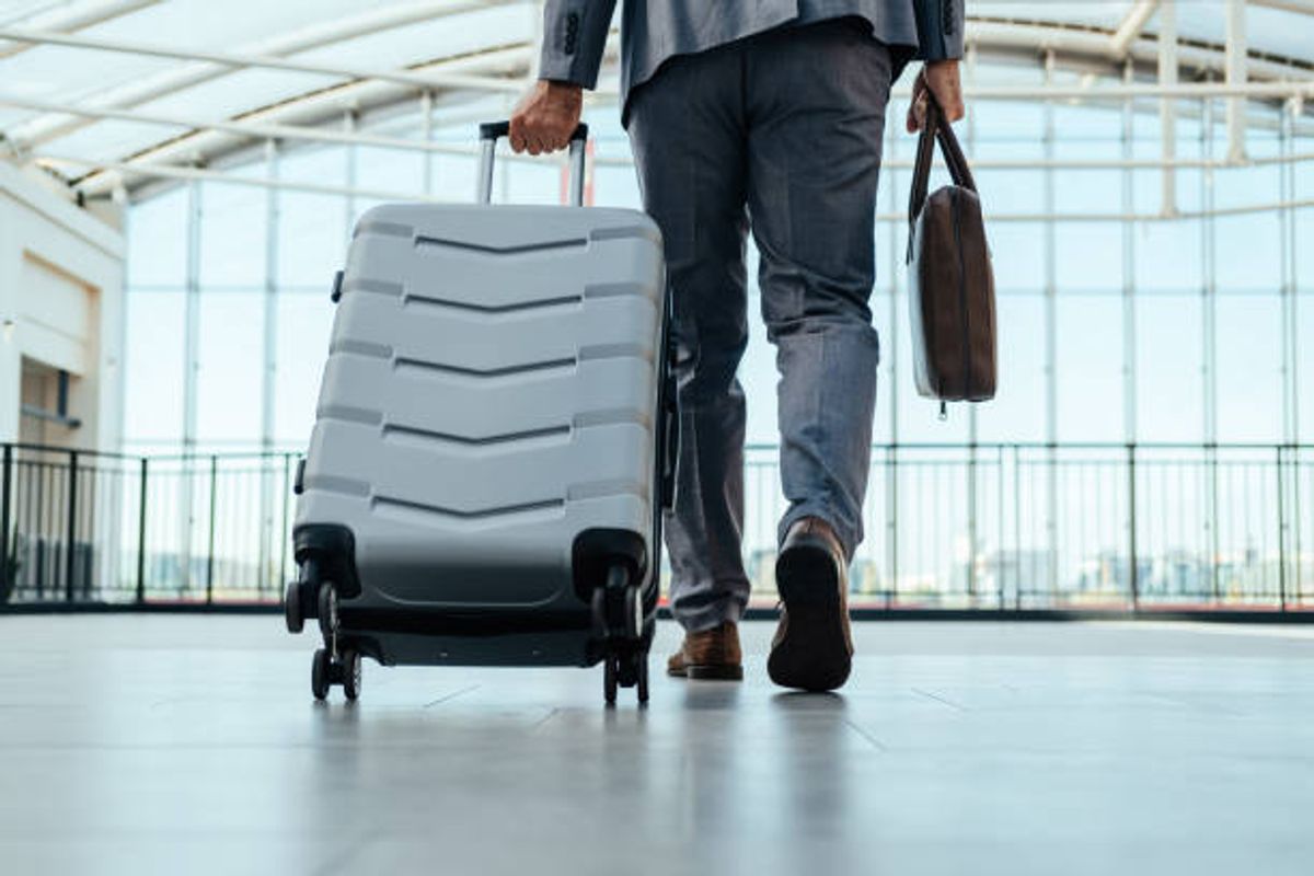 Corporate traveler crossing an airport concourse with a hard-shell suitcase and work bag