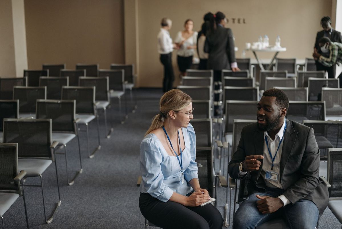 Two people talking in seminar room with empty chairs.