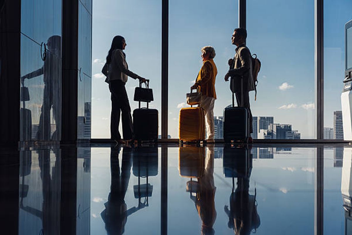 Business colleagues with luggage silhouetted against an airport window at departure