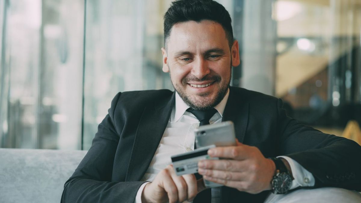 Man in suit using phone and card.
