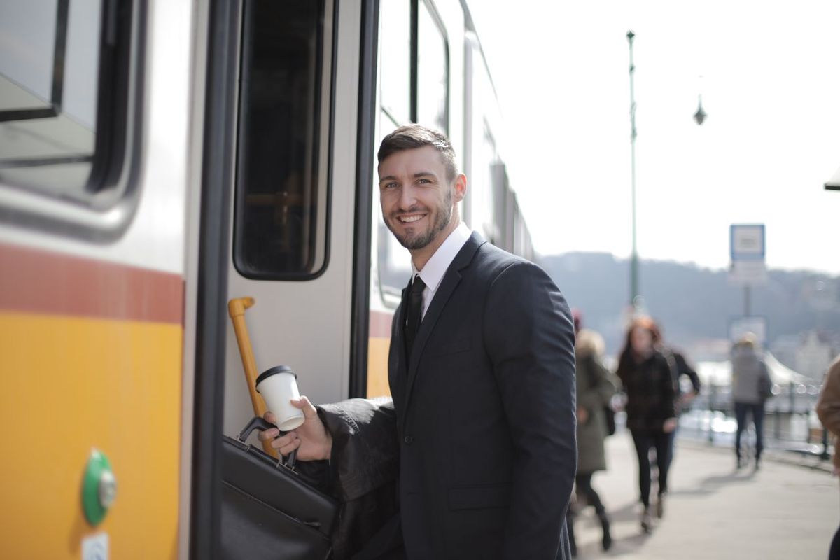 Confident businessman with suitcase and coffee boarding train