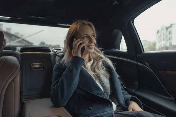 Businesswoman talking on phone while sitting in a luxury car.