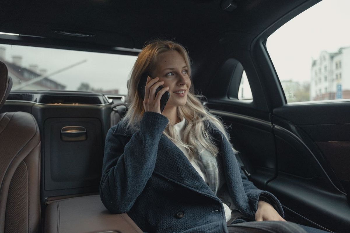 Businesswoman talking on phone while sitting in a luxury car.