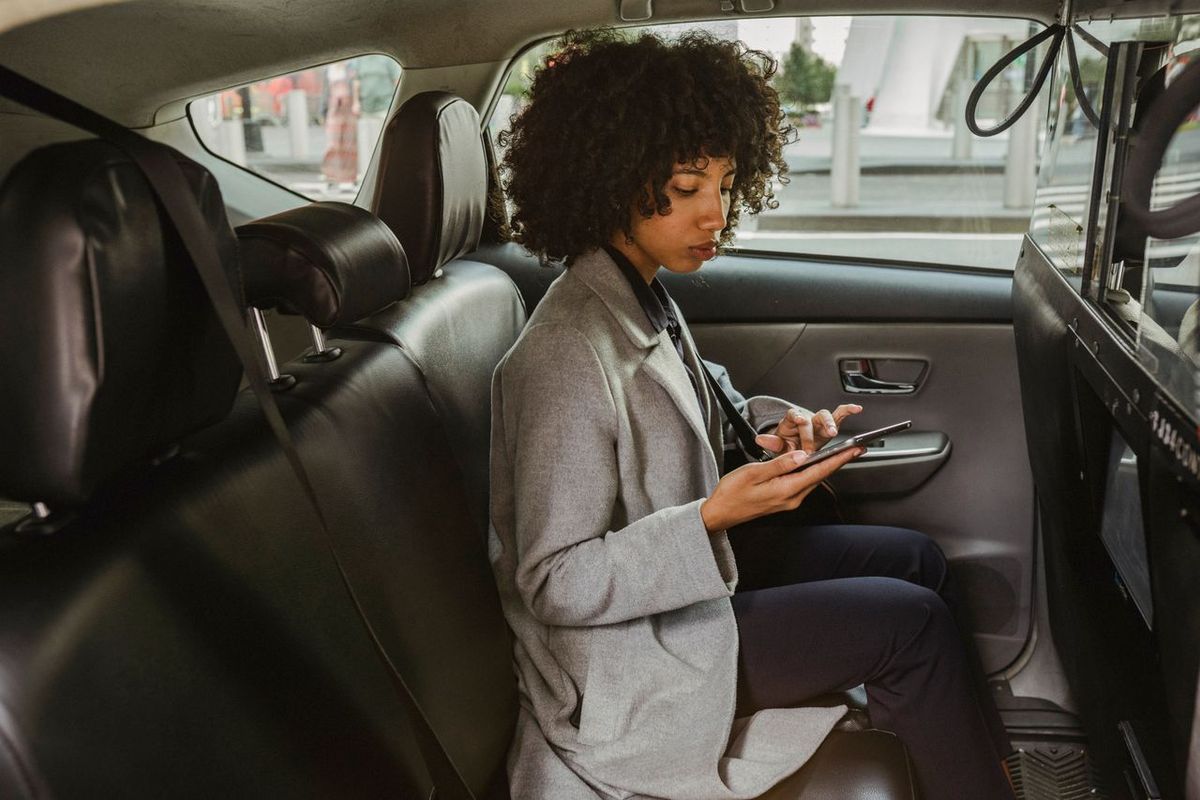 Person in gray coat using smartphone in car.