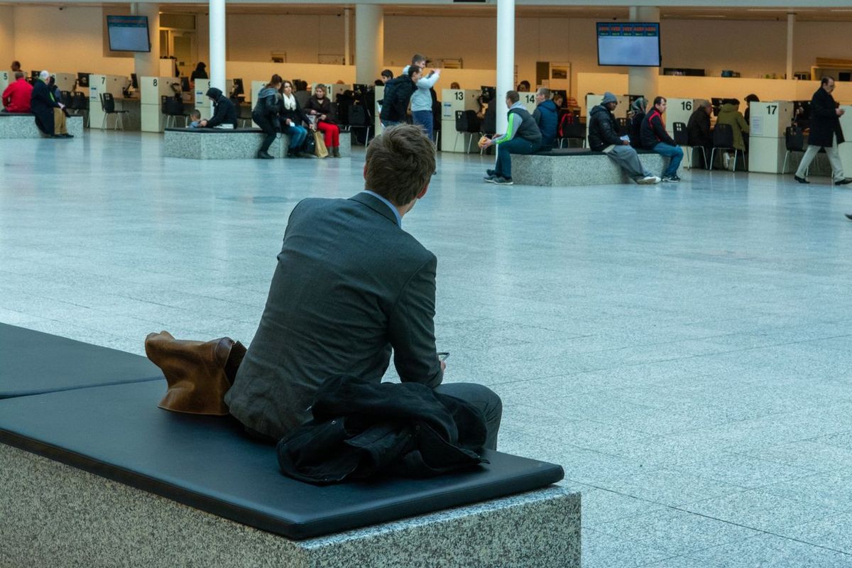Traveler seated in a busy airport terminal waiting area.