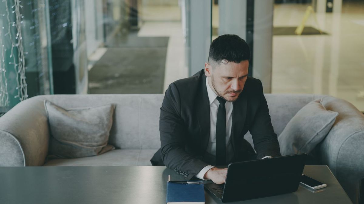 Business traveler working on a laptop while seated in a hotel lounge.