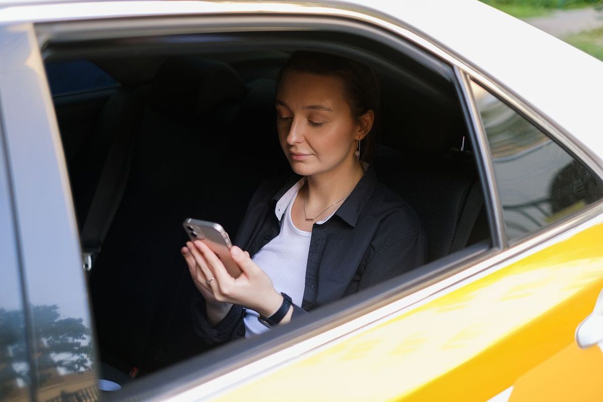 Person in yellow car using smartphone.