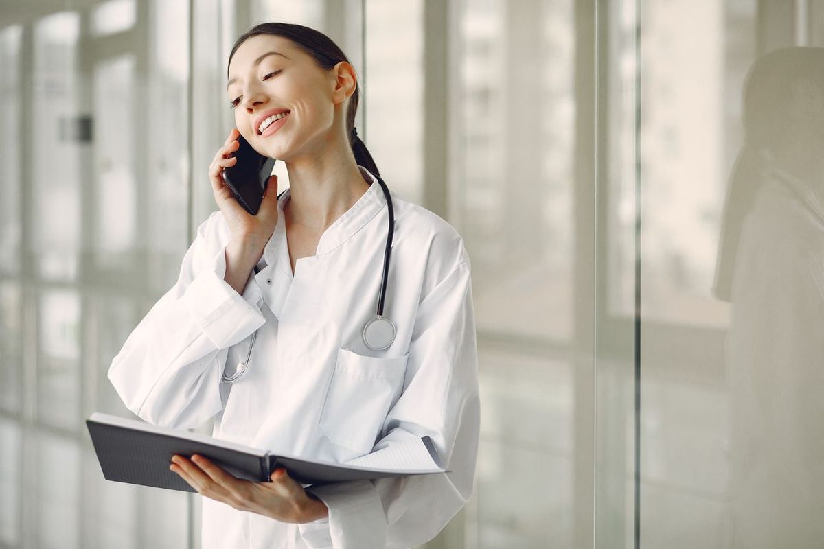Doctor in white coat with stethoscope talking on phone.