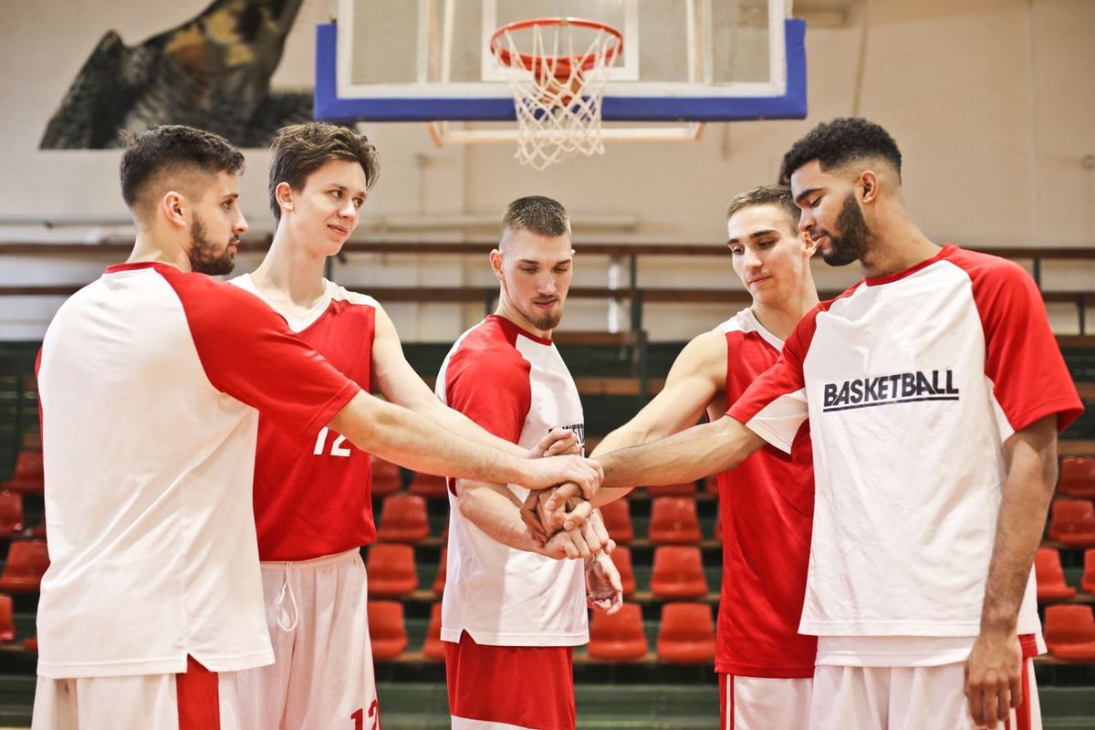 A group of young male basketball players huddle in a gym.