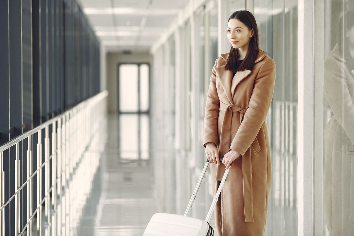 Traveler with a rolling suitcase standing in a hotel corridor.