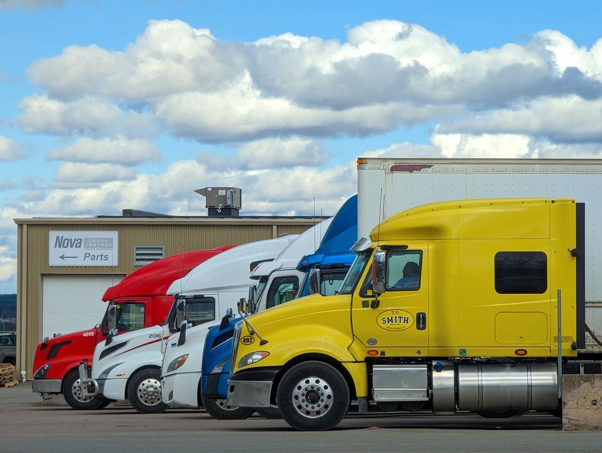 Four semi-trucks parked outside parts service center.