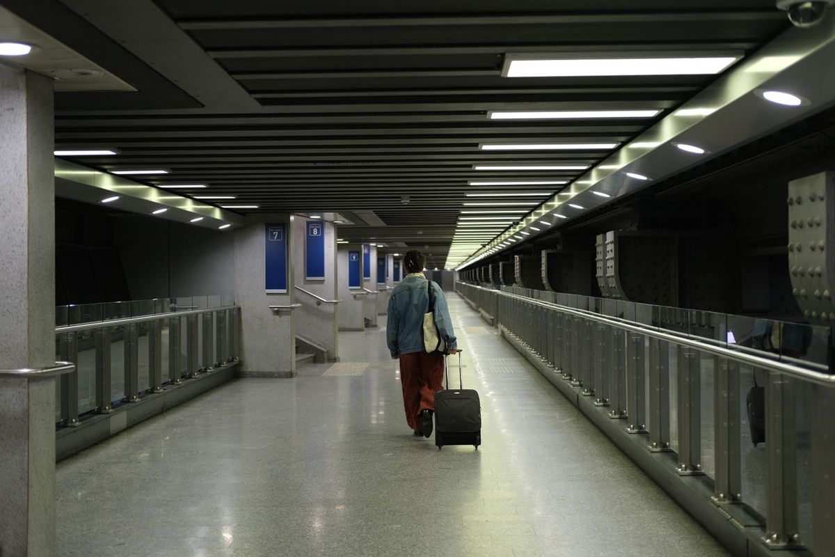 Traveler pulling a suitcase through a modern transit corridor.