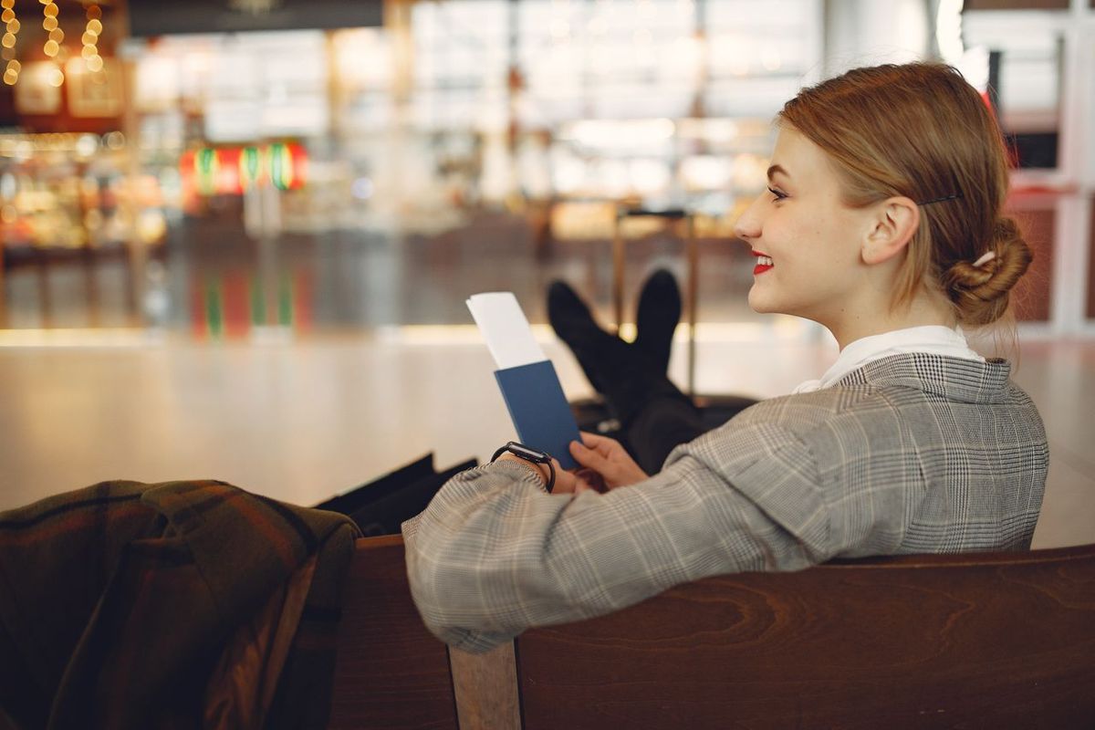 Traveler seated with passport and boarding pass in airport lounge.