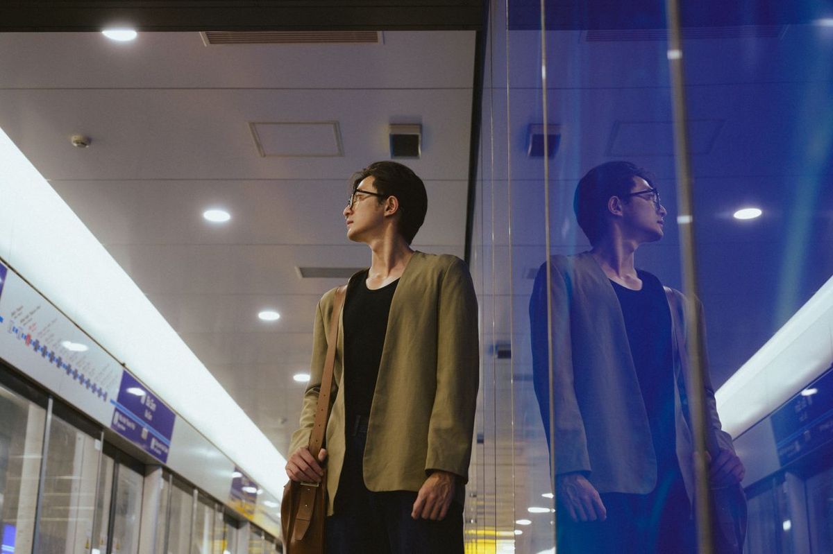 Person with brown jacket and bag in subway station.