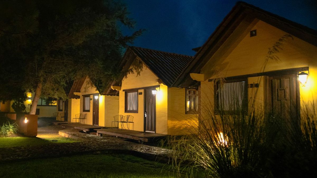 Cozy row of warmly lit lodge cottages at night with trees and landscaped grounds.