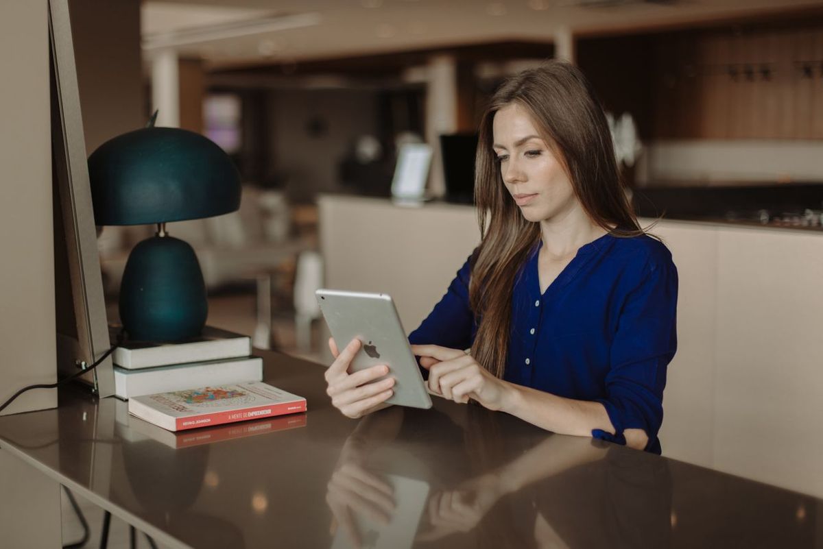 Person in blue shirt using tablet at café table.
