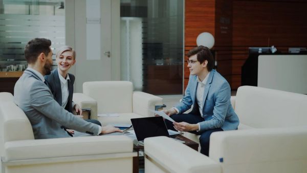Three people in office lounge having a business meeting.
