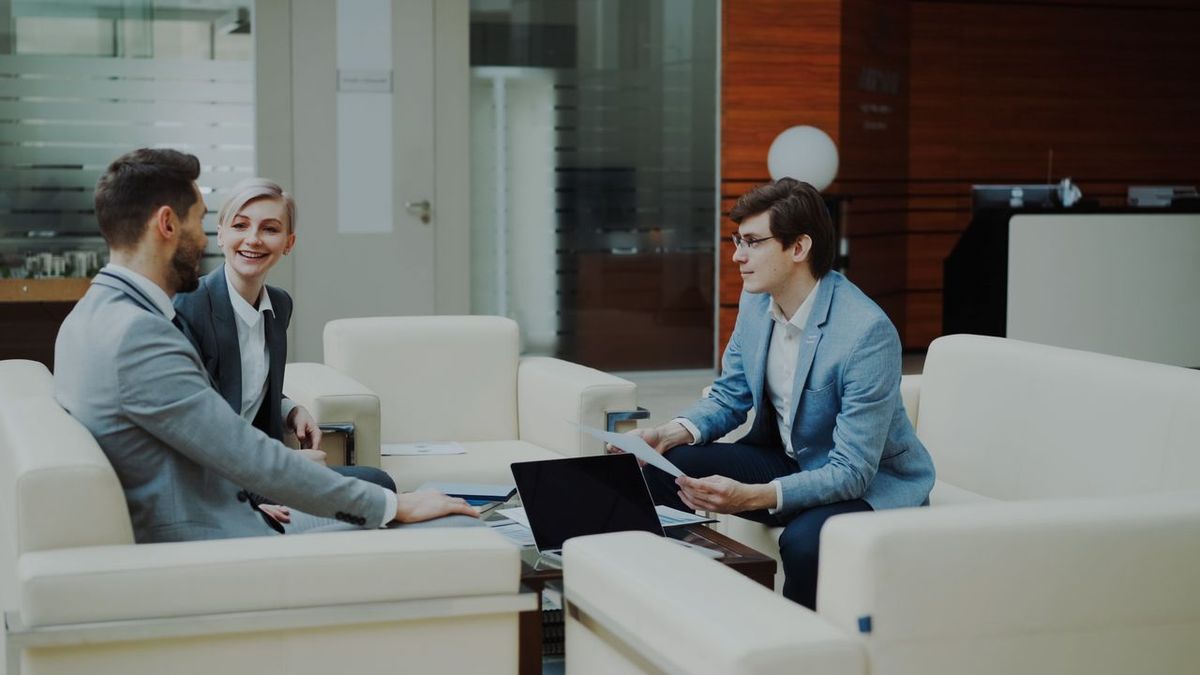 Three people in office lounge having a business meeting.