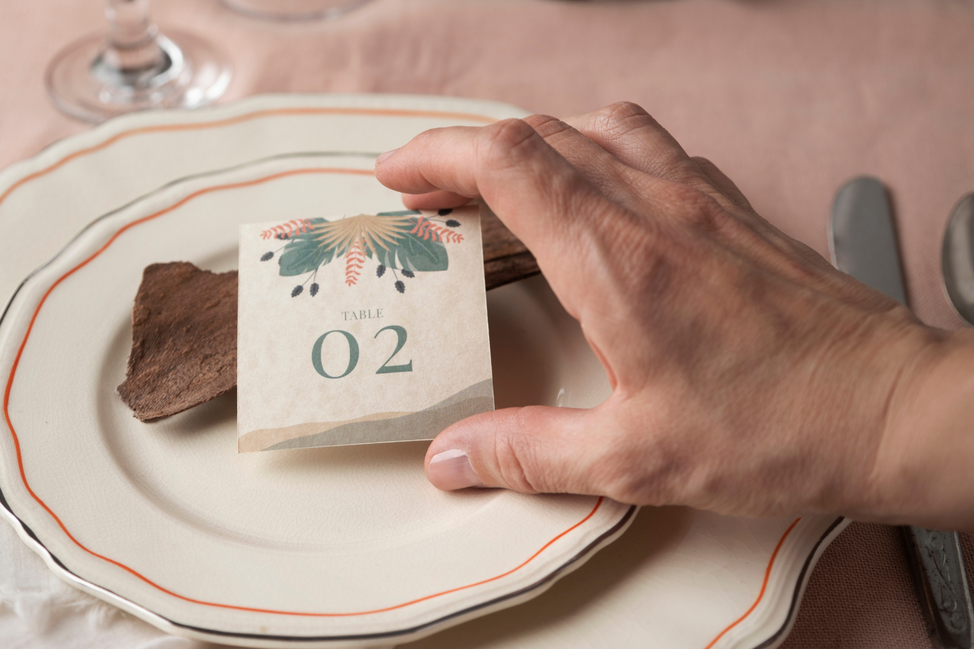 Hand placing a wedding table number card on a decorated place setting