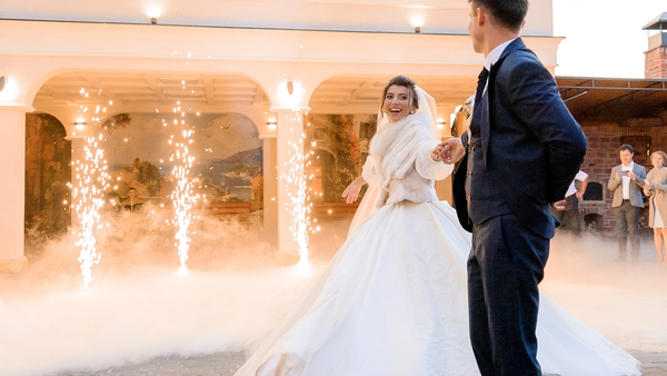 Bride and groom dancing at their reception as wedding guests celebrate in the background