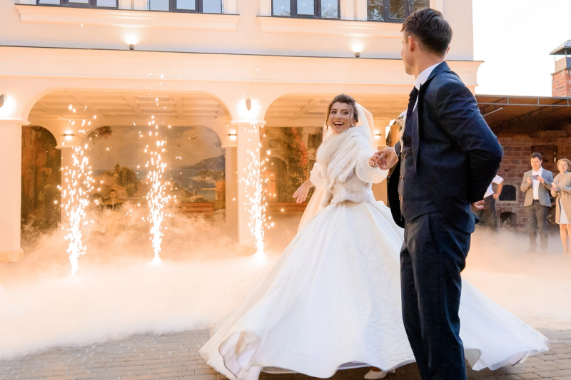 Bride and groom dancing at their reception as wedding guests celebrate in the background