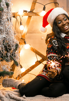 a couple sitting in front of a christmas tree and lights and enjoying the warmth of the season