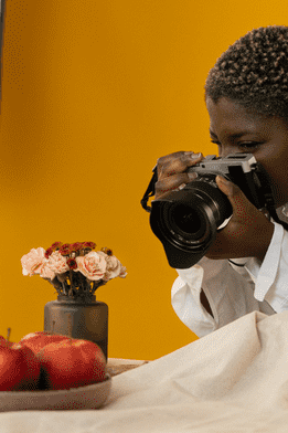a lady photograher taking snapshots of an apple with quality photo composition in mind