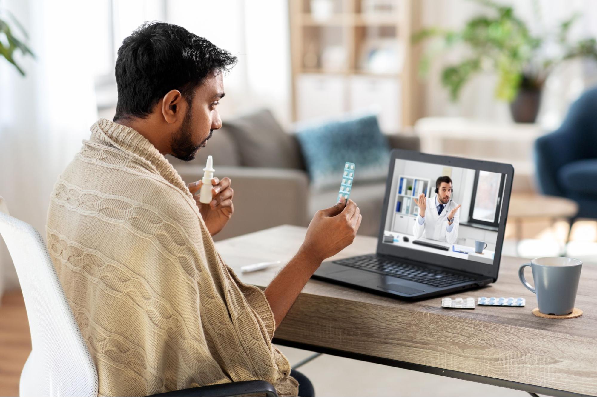 A man seated at a desk, working on a laptop while a tablet rests beside him.