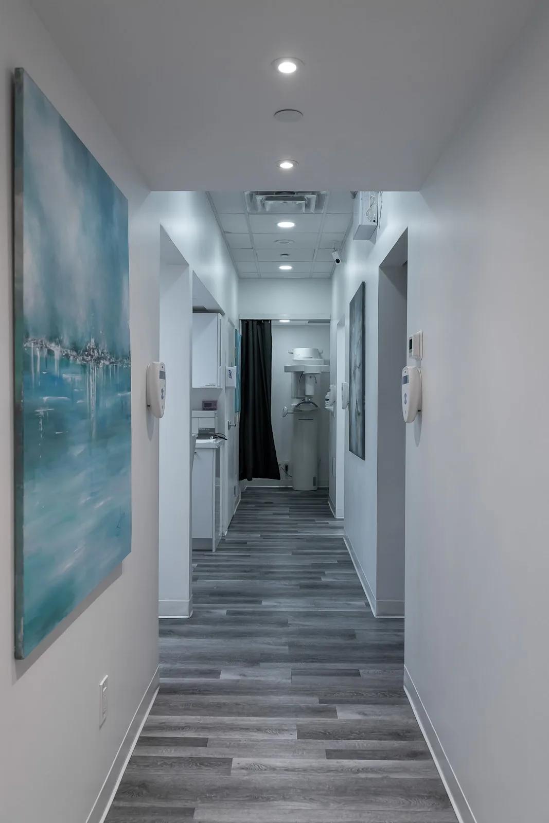 The corridor between the treatment rooms: doorways on both sides, paintings on the walls and the imaging room at the far end