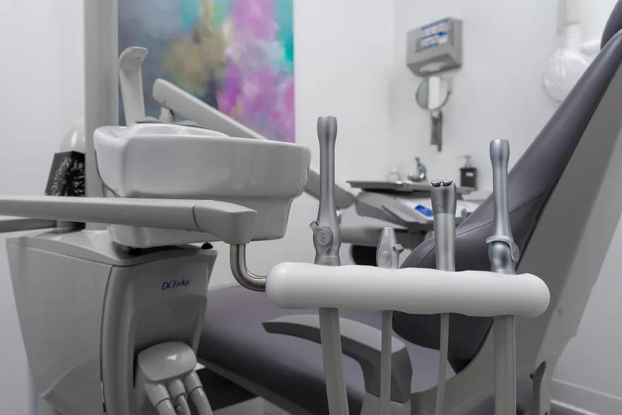 A treatment room at the clinic: the dental chair beside its instrument tray and delivery unit