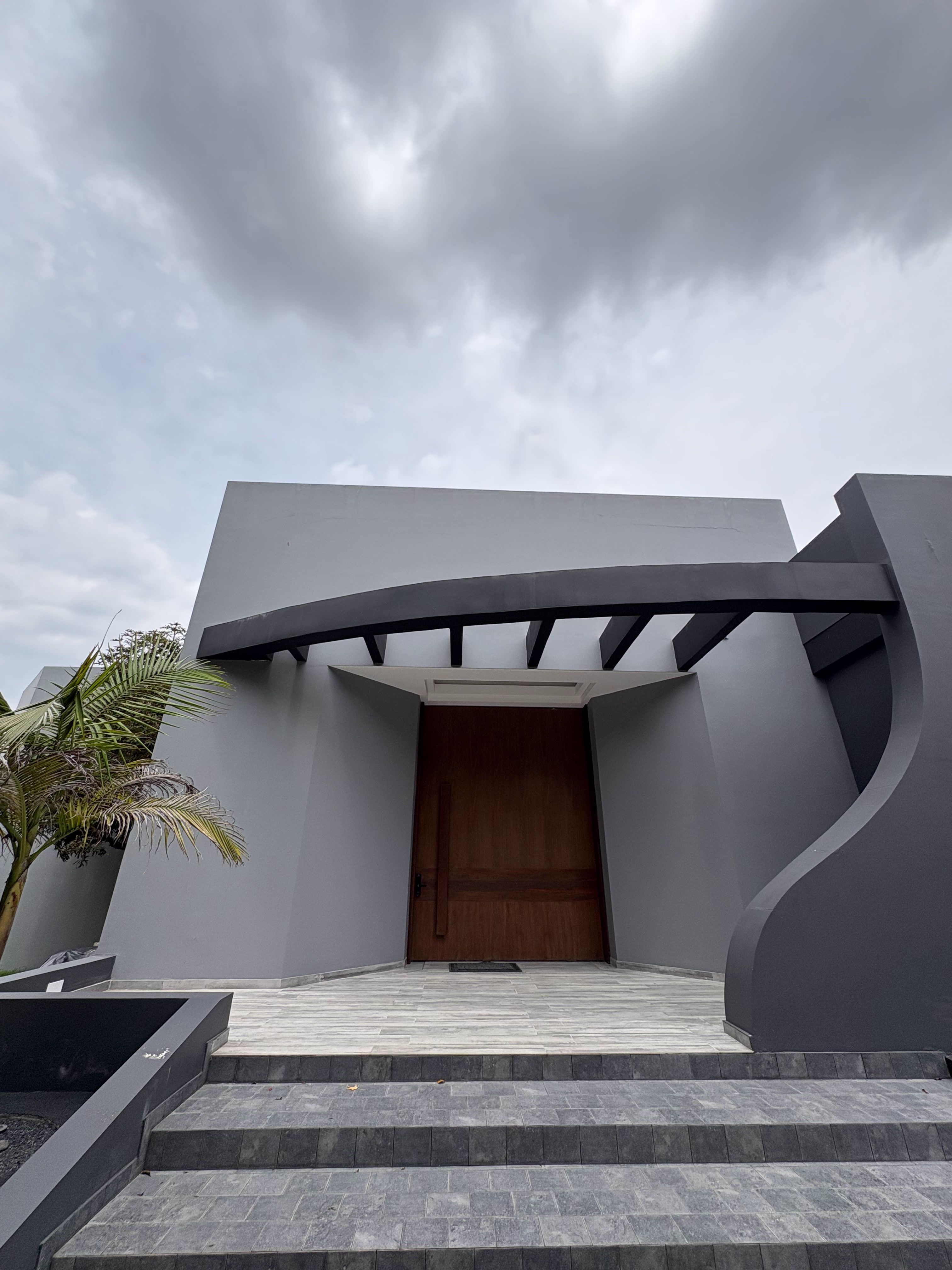 Entrada principal con puerta de madera bajo una pérgola curva