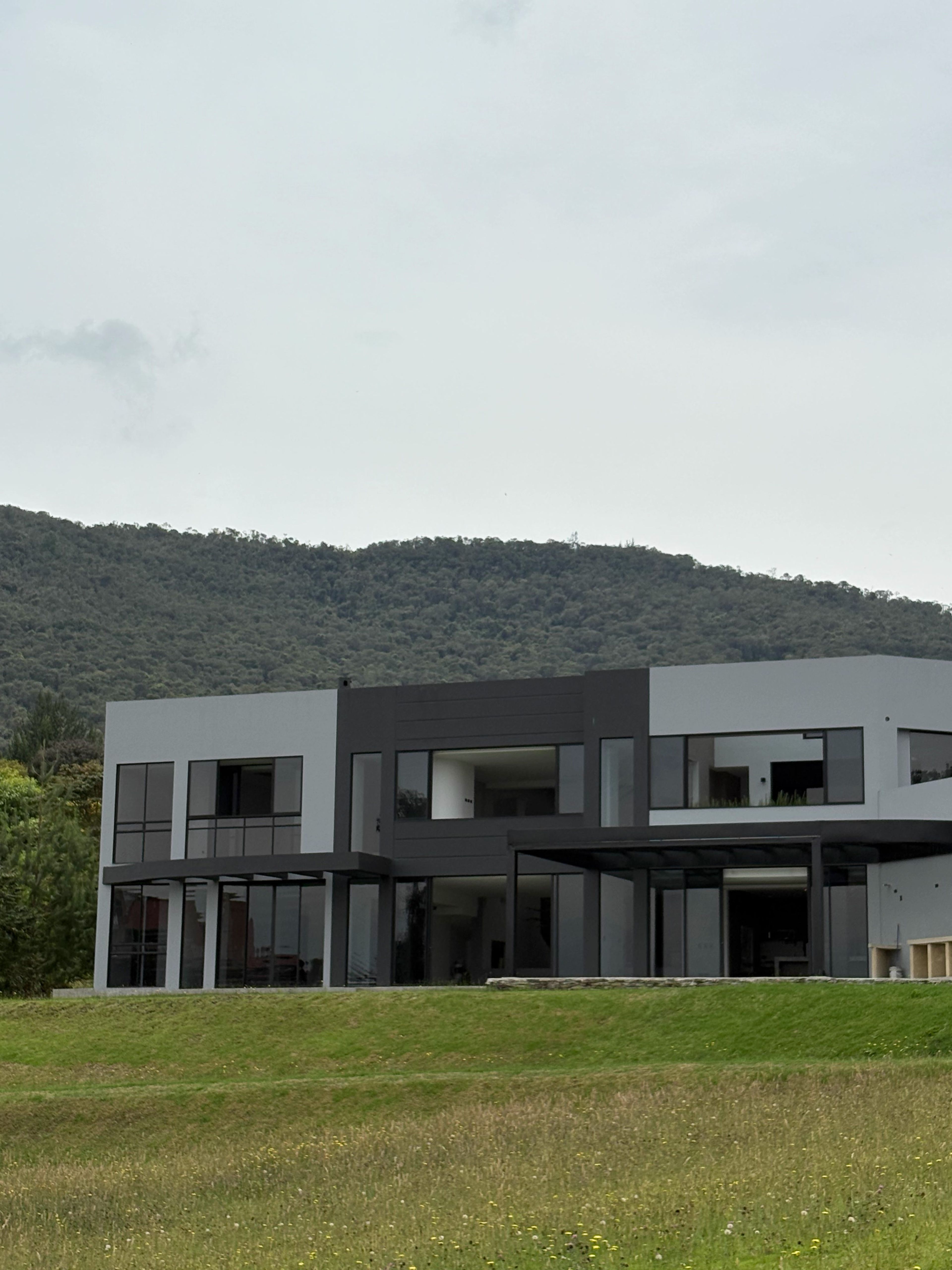 Fachada contemporánea gris y grafito con la montaña boscosa al fondo