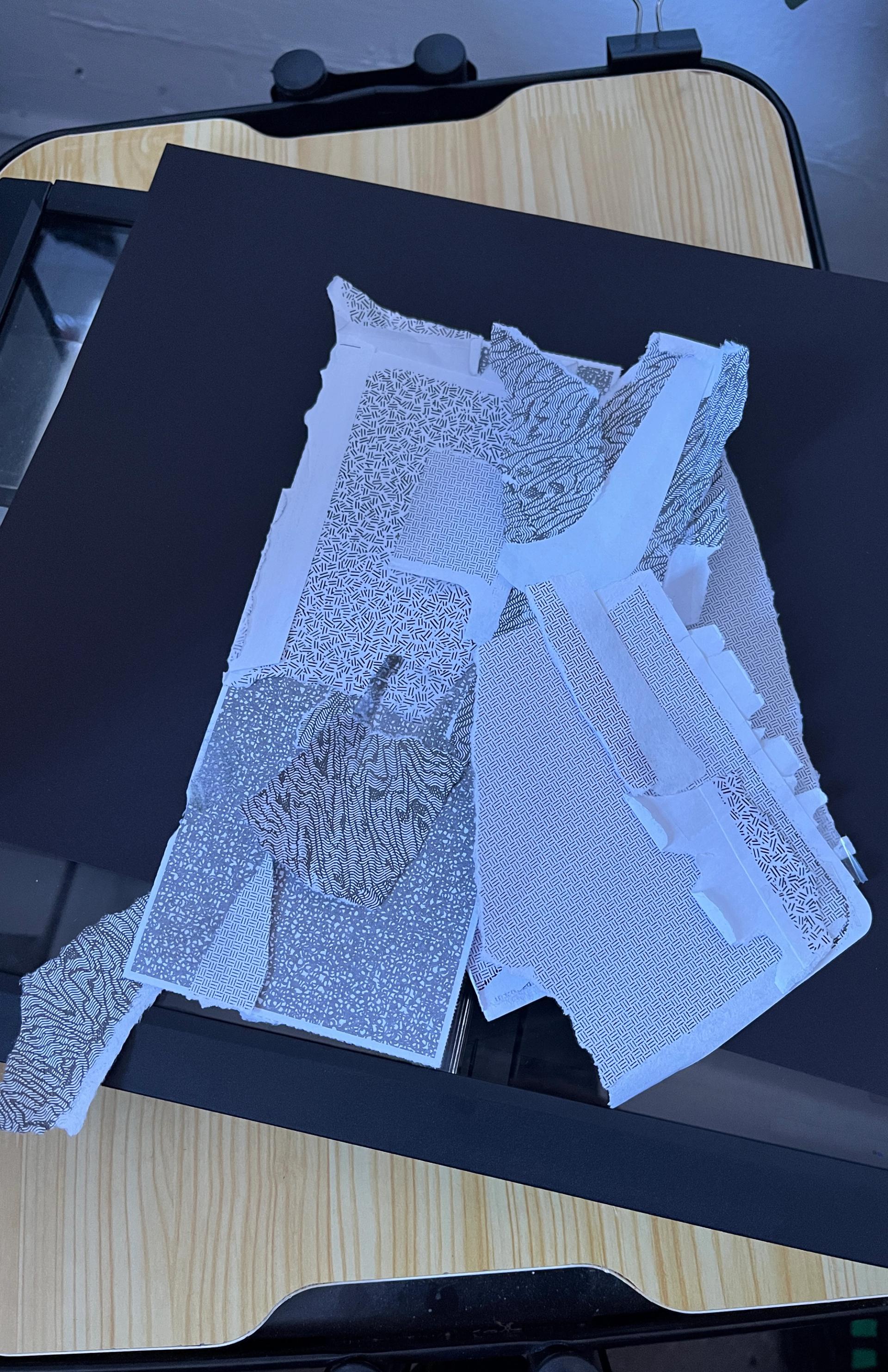 Shreds of ripped-up envelopes with gray and white printed patterns are piled on top of a black surface.